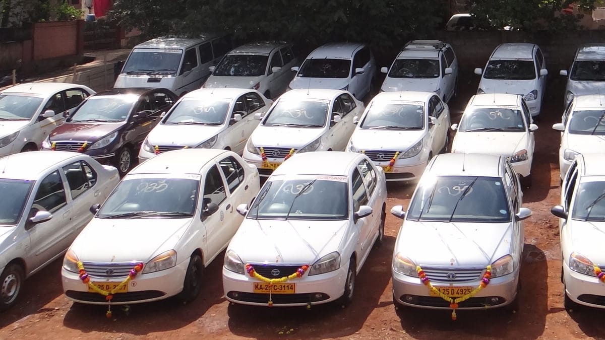 Elevated view of roughly twenty-five white fleet sedans and utility vehicles parked in tight rows