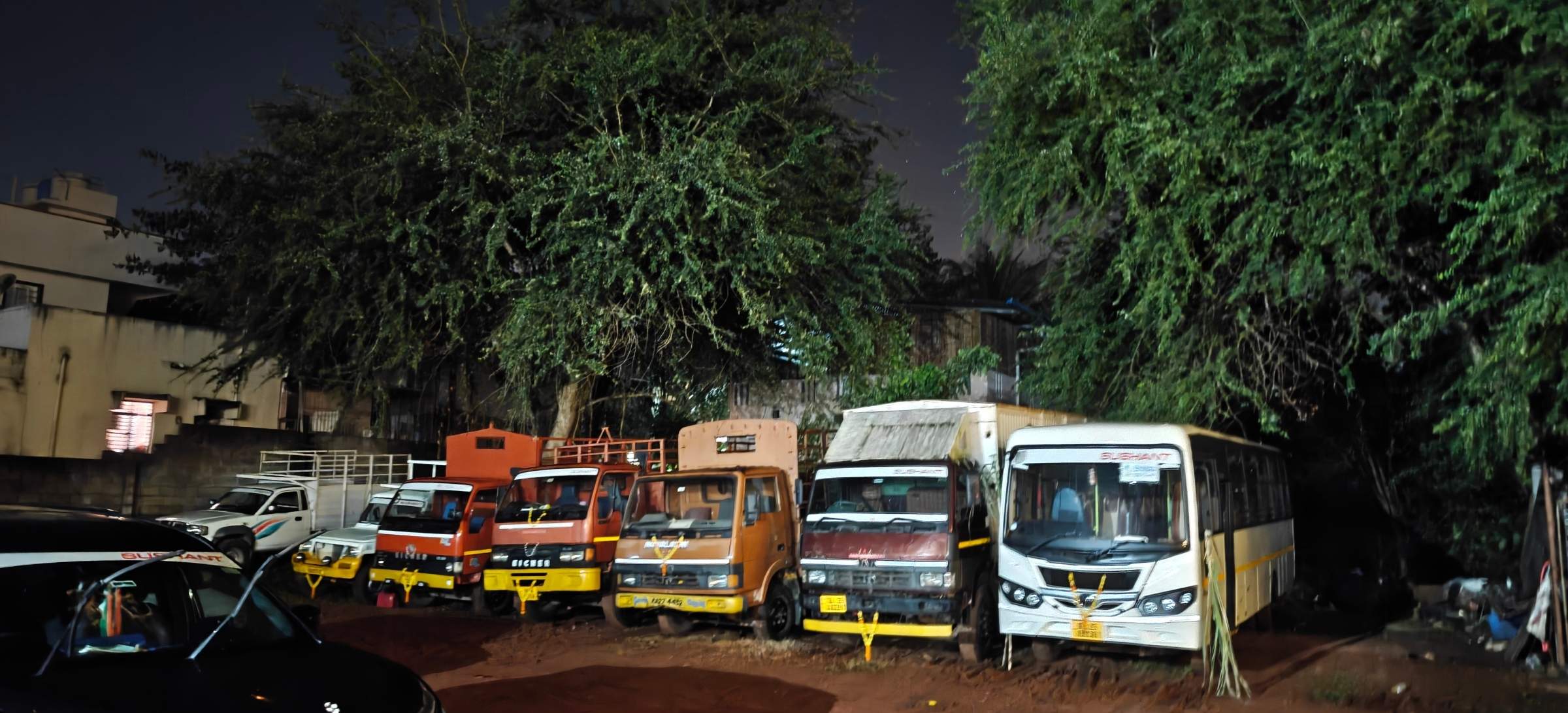 Trucks and a bus parked in a row at night