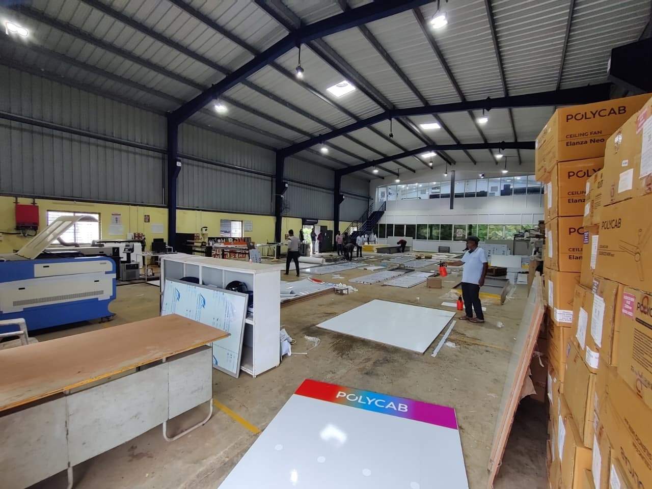 Wide view of the print floor with machines, panels and stacked cartons