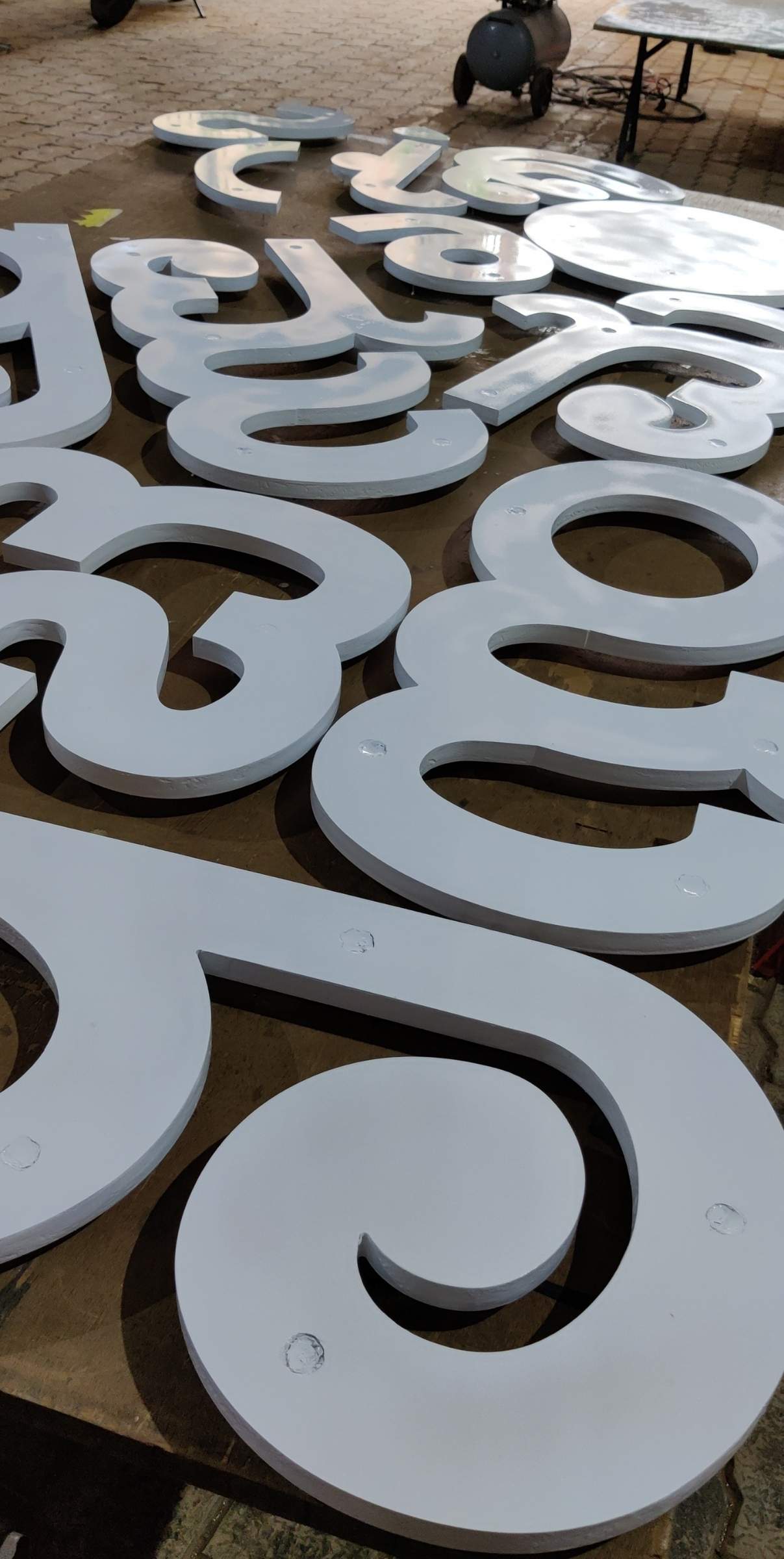 White cut acrylic Kannada letters laid out on the ground before installation