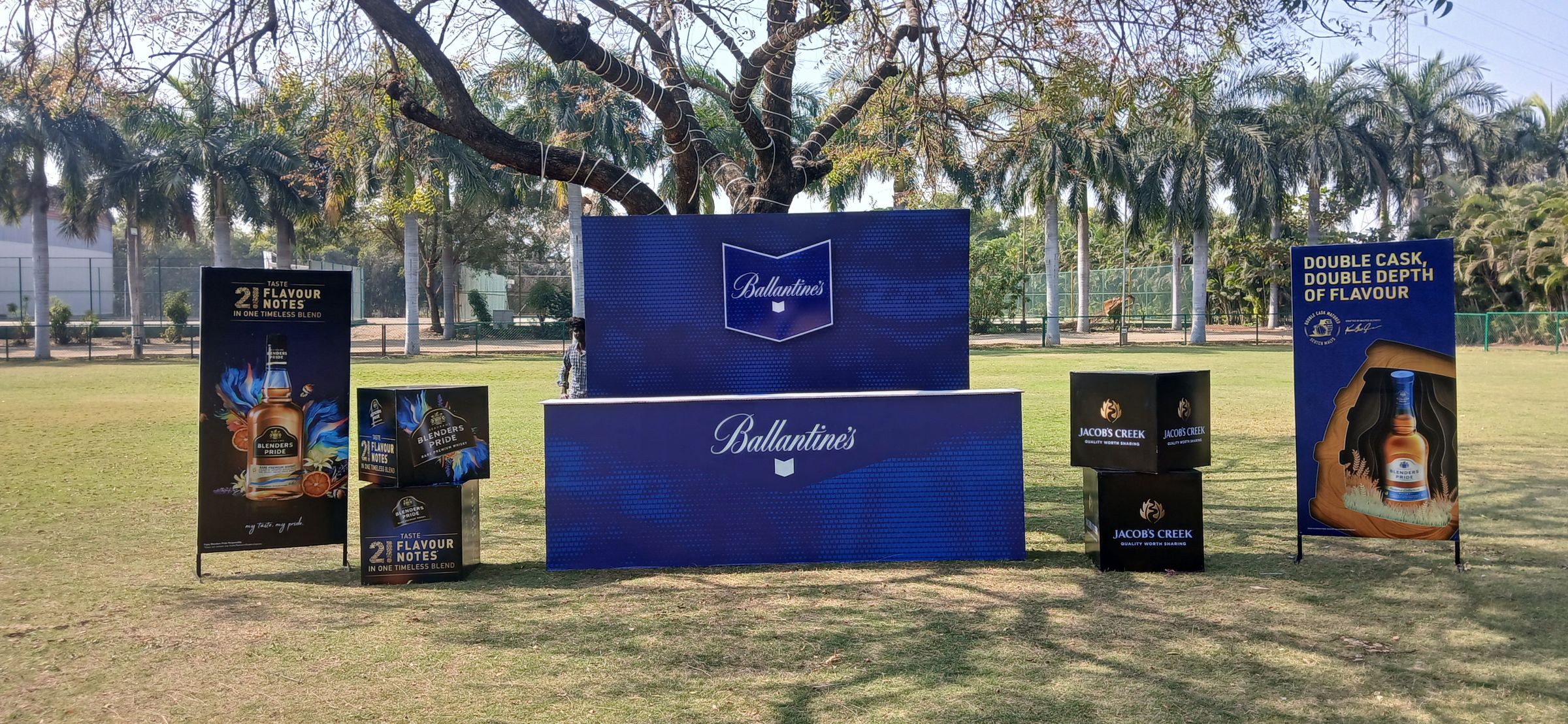 A branded bar counter and standees set up on a lawn