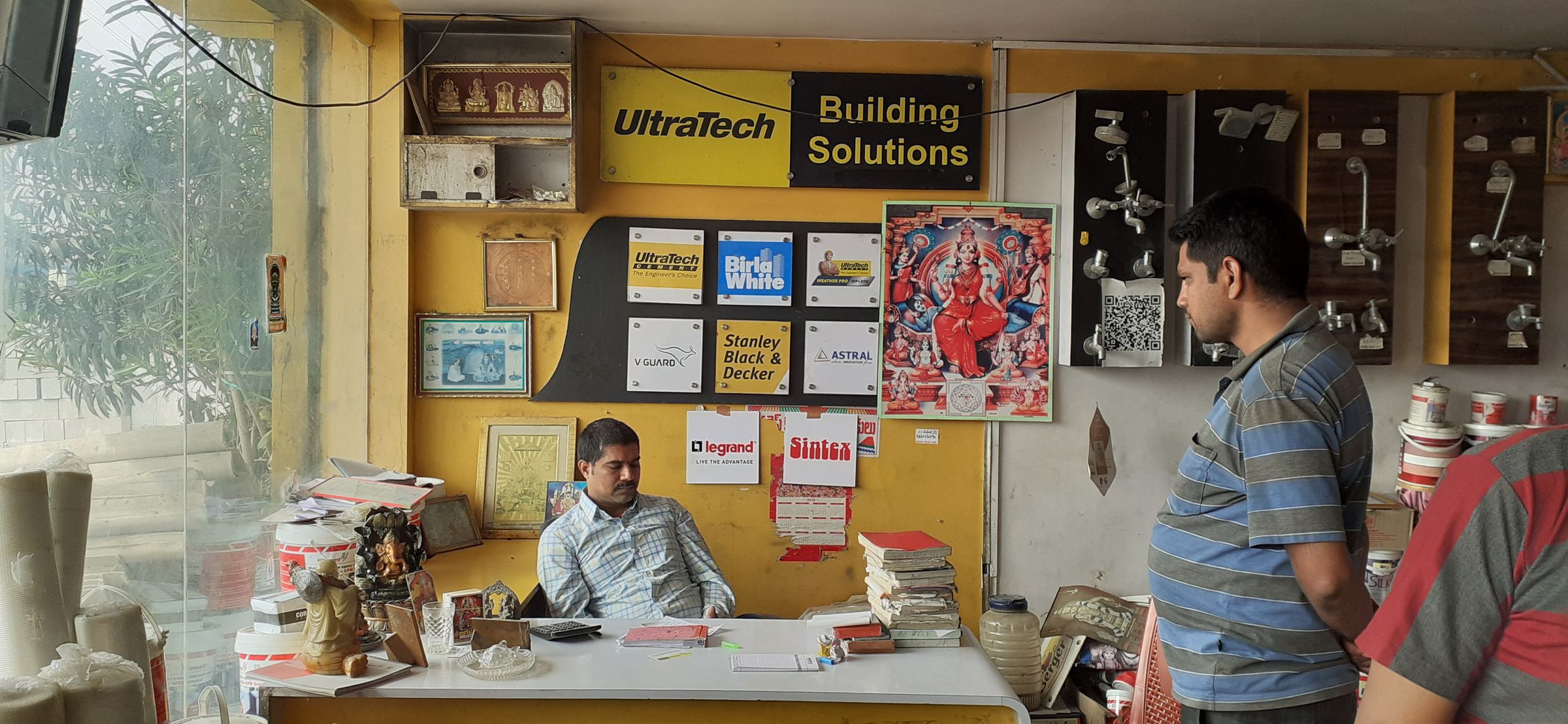 Inside a building-solutions store: branded wall, product display and the dealer's desk